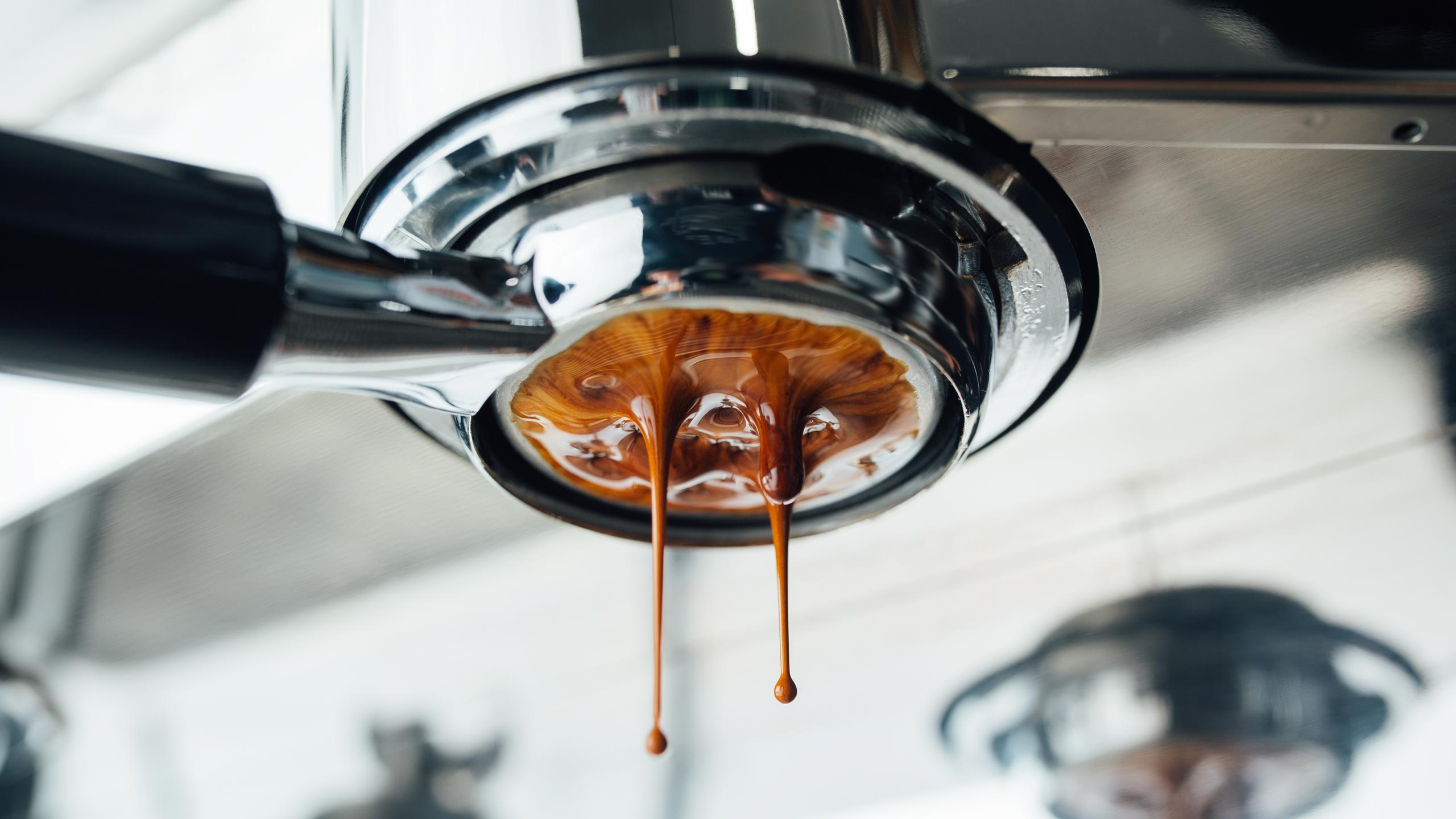 A close-up shot of an espresso portafilter dispensing an espresso shot